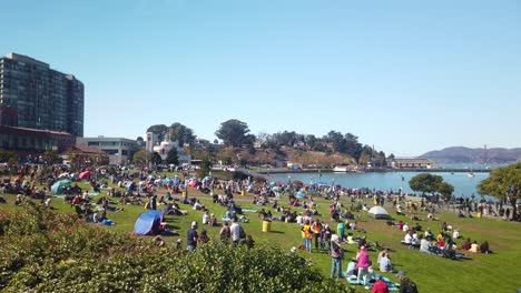 Gimbal-wide-panning-shot-of-crowd-gathered-on-grassy-lawn-at-the-waterfront-for-Fleet-Week-in-San-Francisco,-California