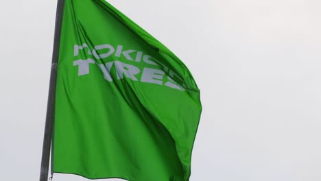 Nokian-Tyres,-Nokian-Renkaat,-flag-flying-in-front-of-their-tire-factory-in-Nokia,-Finland