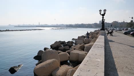 Waterfront-of-Lungomare-Imperatore-Augusto-street-with-fishermen-in-Bari,-Italy-with-lamps