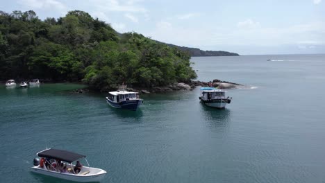 Drone-shot-of-tour-boats-on-the-coastline-of-cloudy-Ilha-Grande,-Brazil