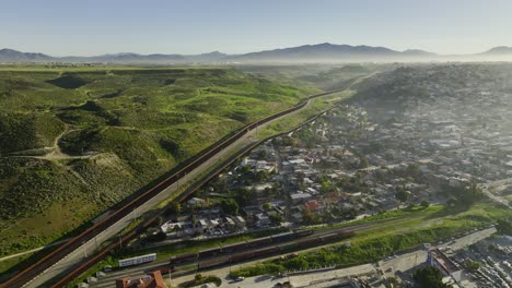 Aerial-view-over-a-shantytown,-following-the-border-wall-between-Mexico-and-USA
