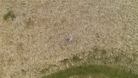 Birds-eye-view-drone-shot-of-a-fiddler-playing-his-violin-outside-by-the-sea-on-a-country-estate-on-the-Isle-of-Lewis,-Outer-Hebrides-of-Scotland,-United-Kingdom
