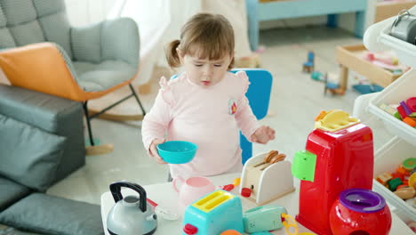 Entzückendes-Kleines-Mädchen,-Das-Zu-Hause-Mit-Spielzeug-Kunststoff-Küchengeräten-Spielt