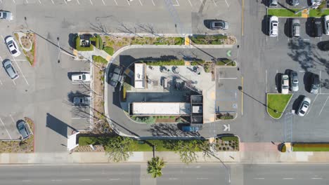 Top-down-aerial-drone-time-lapse-of-a-unique-prefab-rare-Starbucks-coffee-shop,-with-cars-going-through-the-drive-thru-and-the-innovative-design-standing-out