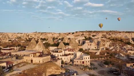 Drone-view-of-Cappadoccia-formations-and-balloons,-Goreme,-Turkey