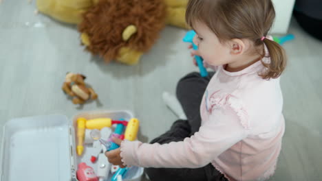 Kleines-Mädchen-Mit-Zöpfen-Spielt-Arzt-Und-überprüft-Mit-Spielzeugwerkzeugen-Aus-Kunststoff-Die-Ohren