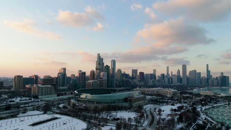 Aerial-view-approaching-the-Solider-field-stadium-and-the-skyline-of-wintry-Chicago,-sunset-in-Illinois,-USA