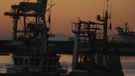 Sines-port-or-harbor-in-Portugal,-ships-and-cranes,-romantic-orange-sunset-sky