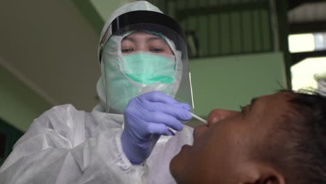 Prueba-De-Coronavirus:-Trabajador-Médico-Que-Toma-Muestras-De-Coronavirus-De-Un-Hombre-Potencialmente-Infectado-Con-Bata-De-Aislamiento-O-Traje-Protector-Y-Máscara-Facial-Quirúrgica
