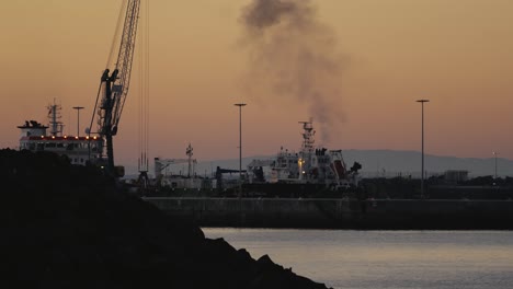 Industrieschiffe-Im-Hafen-Von-Sines-Oder-Im-Hafen-Von-Portugal,-Abendansicht,-Orangefarbener-Himmel