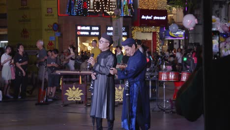 Two-men-performing-on-stage,-singing-at-night-on-?