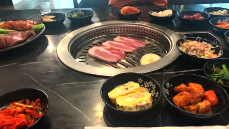 Mouthwatering-Korean-Tabletop-thin-slice-pork-BBQ-with-multiple-side-dishes-on-the-table