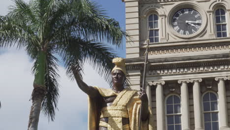 Torso-view-of-the-Gold-King-Kamehameha-Statue-in-Front-of-a-Building-and-Palm-Trees-on-a-Sunny-Day-in-Honolulu,-Hawaii