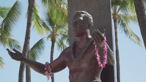 Torso-View-of-the-Duake-Paoa-Kahanamoku-Statue-on-a-Sunny-Breezy-Day-With-Palm-Trees-in-the-Background-at-Waikiki-Beach-in-Hawaii