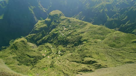 Drone-descending-into-the-crater-of-cirque-de-Mafate-on-La-Reunion-french-island-with-small-village-houses