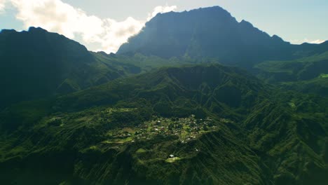 With-the-highest-mountain-in-the-west-indian-ocean-de-Piton-del-Neige-in-the-back-drone-flies-close-to-village-in-the-crater-of-the-cirque-de-Mafate