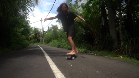 Elegante-Patinador-Montando-En-Surf-Skate-En-Las-Carreteras-De-Bali,-Estilo-De-Vida-Skate