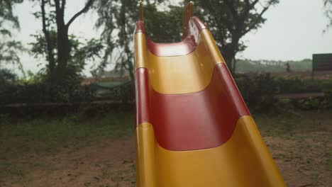 Little-Indian-boy-climbing-up-a-red-and-yello-slide-and-then-sliding-down