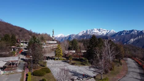 Aerial-View-Over-Consonno-Ghost-Town-In-The-Olginate-Municipality-Of-The-Province-of-Lecco-With-Snow-Capped-Mountains-In-The-Background