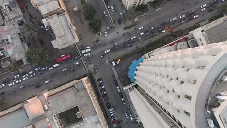 Vista-Aérea-De-Pájaros-Descendiendo-Junto-A-La-Plaza-Del-Banco-Habib-En-Karachi-Con-El-Tráfico-Pasando-Por-Debajo