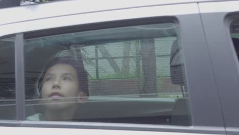 Family-arrives-by-car-at-destination,-the-car-holds-still-and-a-boy-looks-through-the-window-while-he-raises-his-hand-to-the-glass