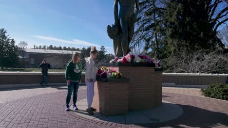 Tow-women-placing-flowers-at-Spartan-Statue-on-the-campus-of-Michigan-State-University-in-memory-of-the-mass-shooting-victims-in-2023