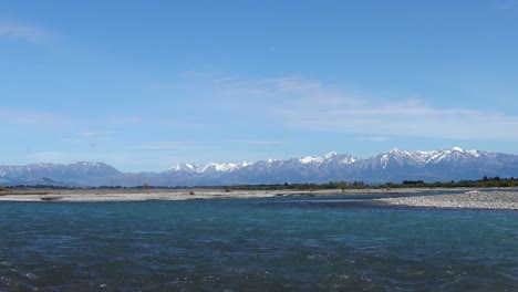 River-flows-steadily-before-snow-topped-foothills-on-a-clear-summer's-day---Waimakariri-River