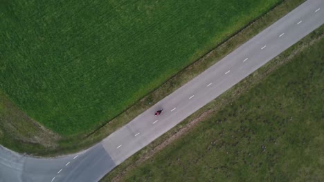 Aerial-drone-shot-of-motorcyclist-driving-down-a-bend-road