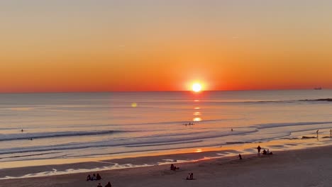 Luftaufnahmen---Jogger-An-Einem-Einsamen-Sandstrand-Läuft-Bei-Sonnenuntergang-Mit-Lichtreflexion-Auf-Der-Meeresoberfläche-Während-Des-Sonnenuntergangs