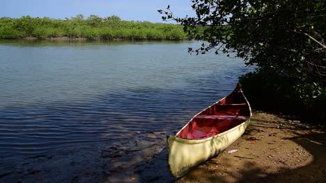 Red-and-white-canoe-laying-in-the-sand-in-the-mangroves-of-Puerto-Pizarro,-Tumbes-Peru