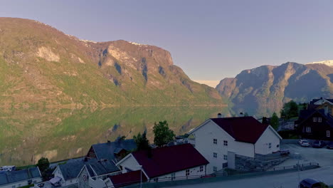 Un-Fiordo-En-Noruega-Con-Un-Pueblo-Junto-Al-Lago-Y-El-Cielo-Reflejándose-En-El-Agua---Revelación-Aérea-Ascendente