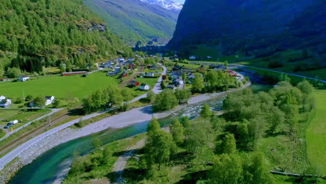 Aerial-flyover-beautiful-river-in-village-between-green-mountains-during-sunny-day,Norway