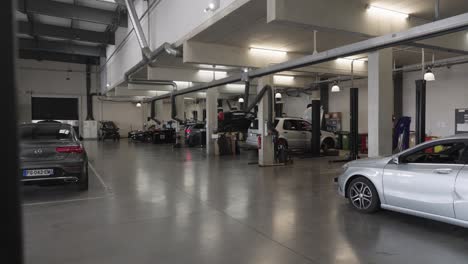 Revealing-shot-of-Mercedes-Benz-cars-being-worked-on-in-a-garage-by-mechanics