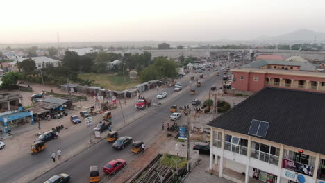 Typical-car-and-tuk-tuk-motorcycle-taxi-traffic-in-Jalingo-town,-Nigeria---ascending-aerial-view