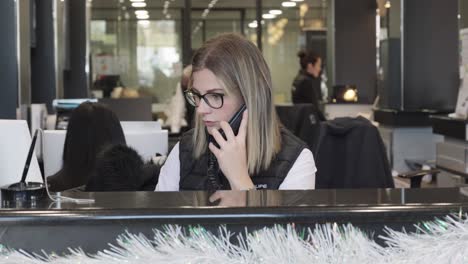 Rotating-shot-of-a-young-female-receptionist-speaking-with-a-client-over-the-phone