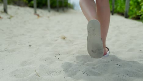 Female-feet-with-sandals-walking-in-soft-sand-in-slow-motion