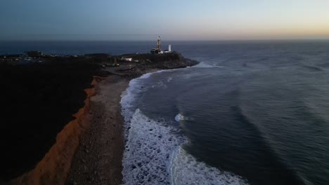 Sunrise-Drone-flight-near-montauk-point-light-house-in-camp-hero-during-the-winter-with-the-shore-and-waves-slowly-coming-in