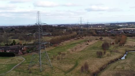 Electricity-distribution-power-pylon-overlooking-British-parkland-countryside,-Aerial-view-rising-forward