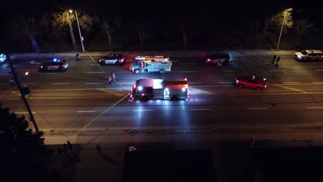Aerial-footage-of-emergency-services-responding-to-a-car-crash-at-night,-showcasing-police,-fire,-and-ambulance-vehicles-in-action