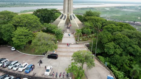 Vista-Aérea-De-Turistas-Visitando-Un-Monumento-En-La-Cima-De-Una-Colina-En-Lambaré,-Paraguay