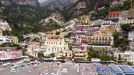 Aerial-drone-footage-establish-scene-of-Marina-Grande-beach,-church-of-Santa-Maria-Assunta-in-Positano,-Amalfi-coast,-Campania,-Italy