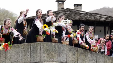 Pretty-Bulgarian-maiden-girls-in-colourful-traditional-dress-perform-ritual-of-throwing-flowers-into-river-from-bridge