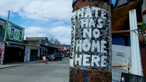 Hate-Has-No-Home-Here-poster-taped-on-a-post-in-Kensington-Market,-downtown-Toronto,-pan
