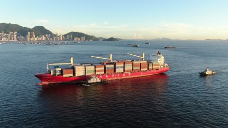 Large-Container-Ship-leaving-Hong-Kong-bay-under-Stonecutters-bridge,-Aerial-view