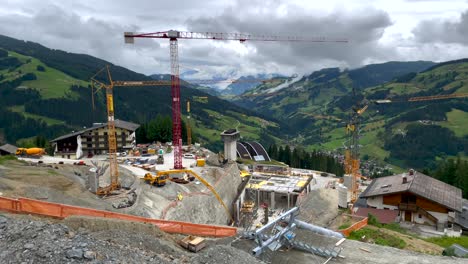 Pan-aerial-shot-of-gigantic-construction-site-in-mountains-during-cloudy-day---Build-of-new-modern-ski-lift-resort-in-Austria