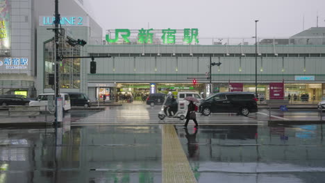 Verkehr-Fährt-Auf-Nasser-Straße-Vor-Dem-Bahnhof-Shinjuku-Jr.,-Nachdem-Es-In-Tokio,-Japan,-Geschneit-Und-Geregnet-Hat