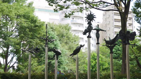 Statues-of-Japanese-creatures-sit-amongst-trees-in-a-tranquil-Tokyo-park-with-modern-apartment-blocks-in-the-background