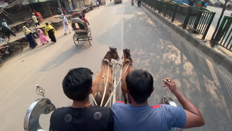 Two-horses-pulling-carriage-in-downtown-of-Dhaka,-POV-view