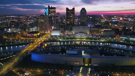 Aerial-view-over-the-COSI-center-towards-the-Skyline-of-Columbus,-colorful-dusk-sky-in-Ohio,-USA---tilt,-drone-shot