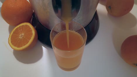 Orange-juice-pouring-in-glass-on-white-table